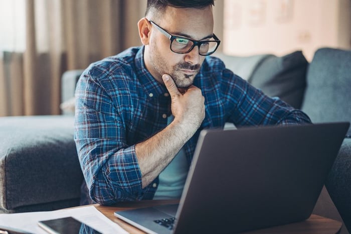 Man with glasses looking at laptop.