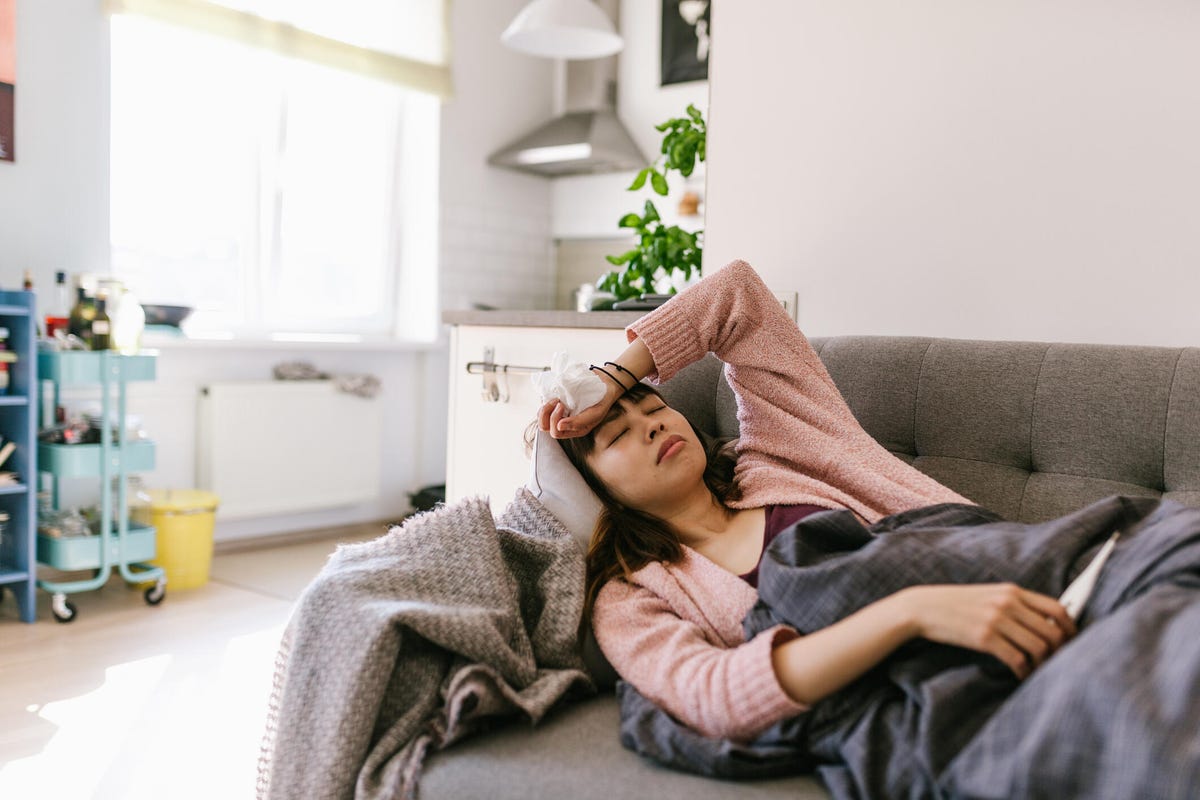 A person laying on the couch with their hand on their forehead