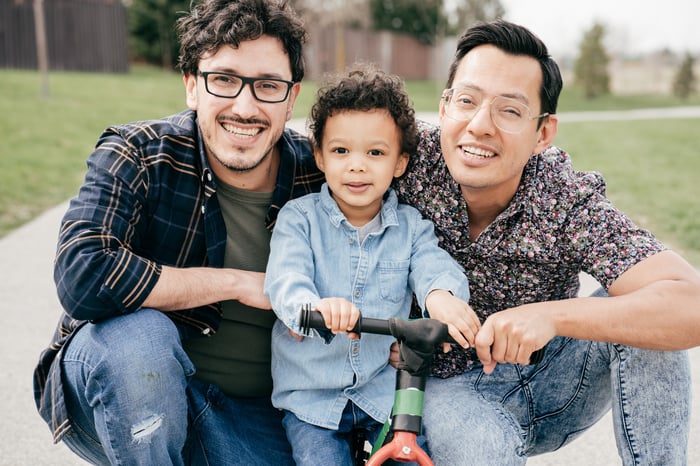 A family is shown, outdoors and smiling.