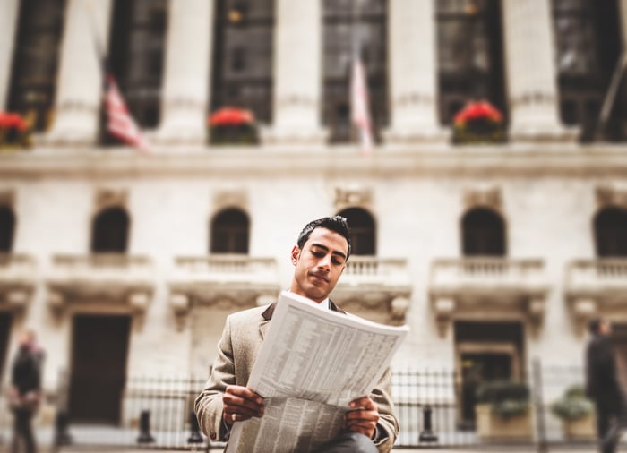 Investor reading newspaper on Wall Street.