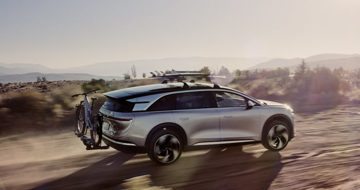 A silver Lucid Gravity, a large electric luxury SUV, on a desert landscape. 