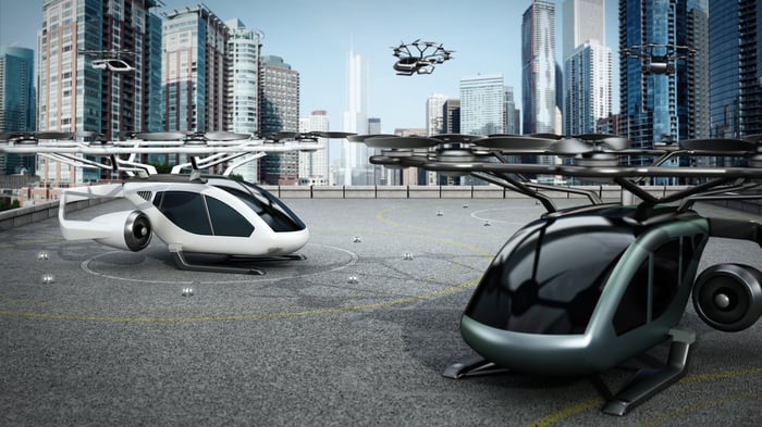 Rendering of futuristic aircraft on a rooftop with a modern city in the background. 