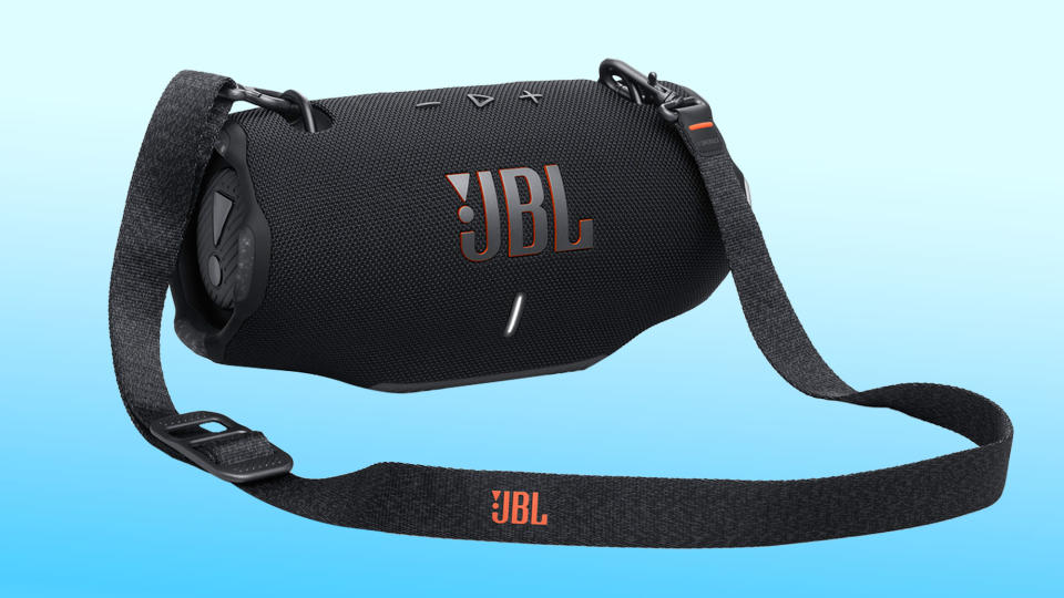 The JBL Xtreme 4 speaker with shoulder strap seen against a blue and white gradient background.