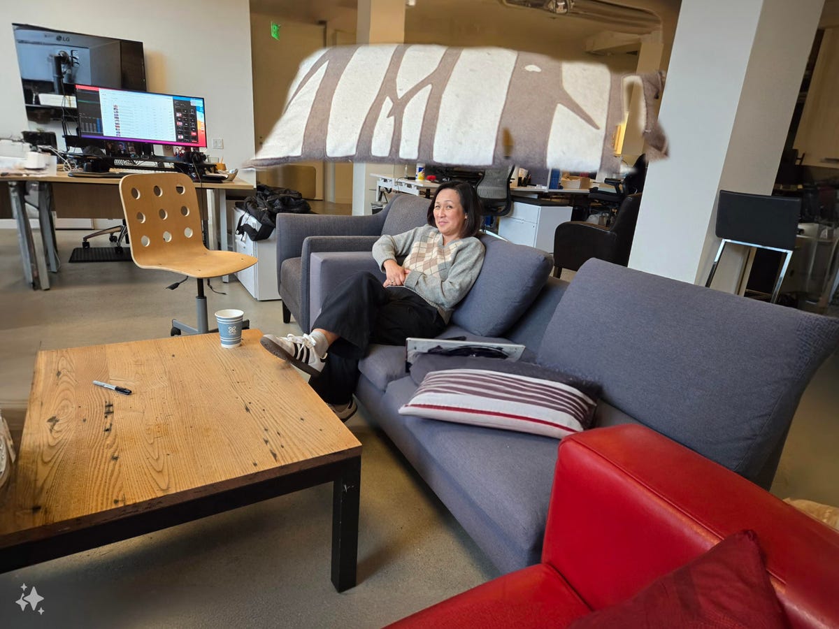 A woman sitting on a couch with a giant pillow floating above