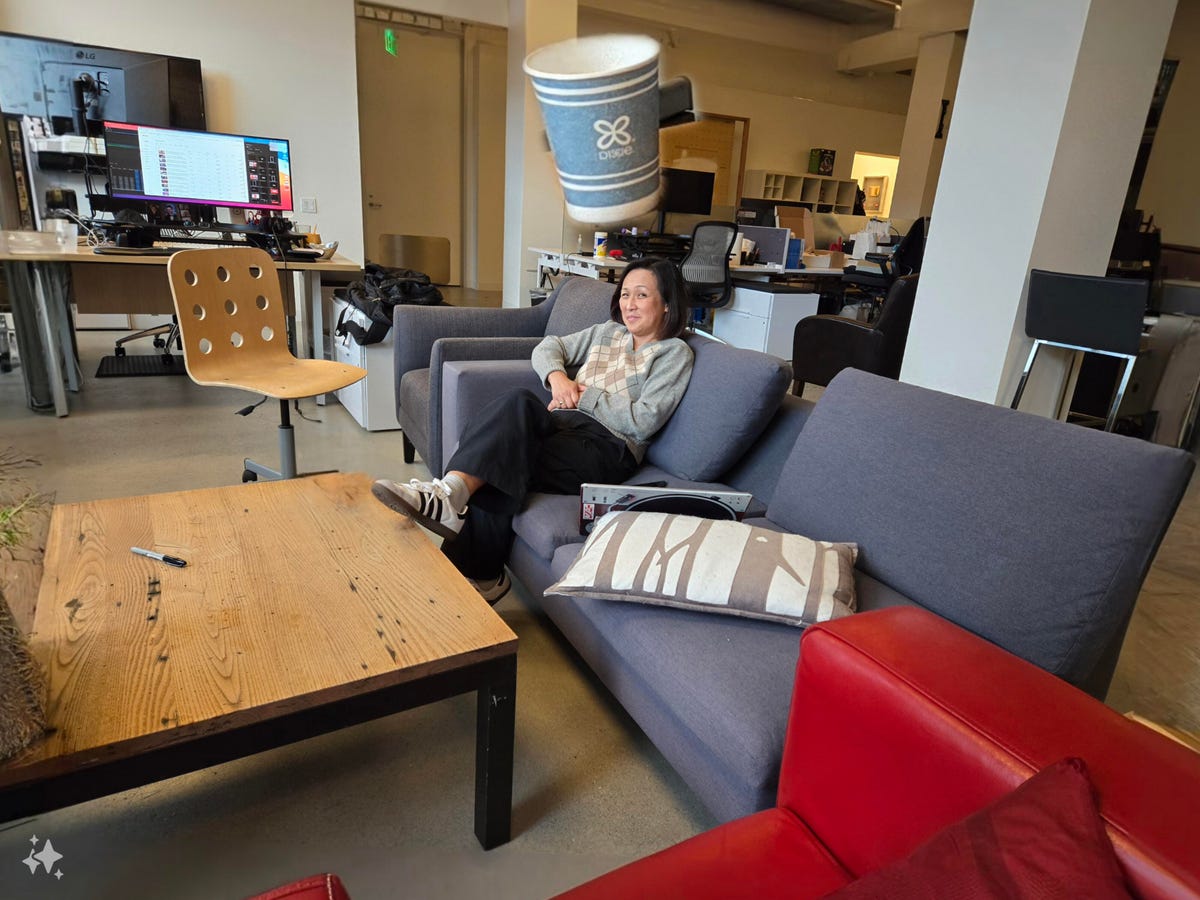 A woman sitting on a couch with a giant coffee cup floating above