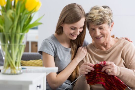 A grandma knitting while her teenage daughter looks on