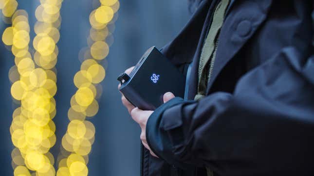 A photo of a person putting the UZE Jacket power bank inside the pocket it lives and charges in. 