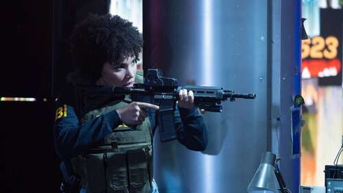 Emmy Raver-Lampman aims a rifle in a still from The Beekeeper