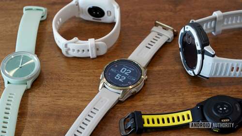 A variety of Garmin wearables rest on a wooden surface.