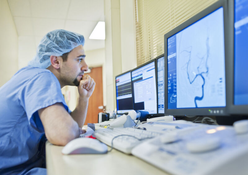 A medical technician looks at a scan on a computer monitor.