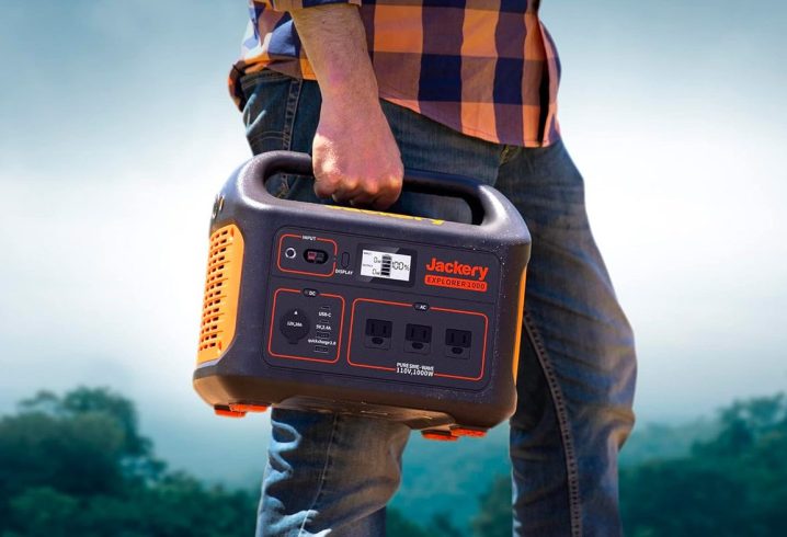 A man carries the Jackery Explorer 1000 portable power station with trees in the background.