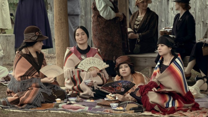 Lily Gladstone and a group of other women sit around a celebration.