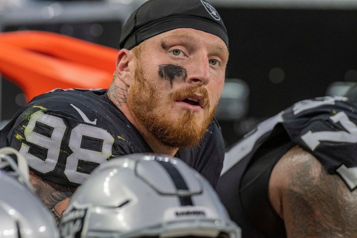 Maxx Crosby sits on the sideline and stares.