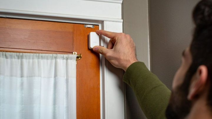 A person placing a Wyze sensor on a door.