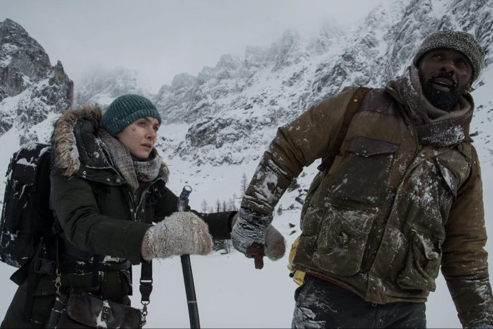 A man and woman walks through the snow in a mountain.