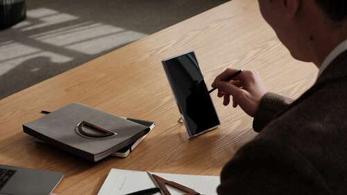 Someone using the S Pen with the phone propped up on a desk