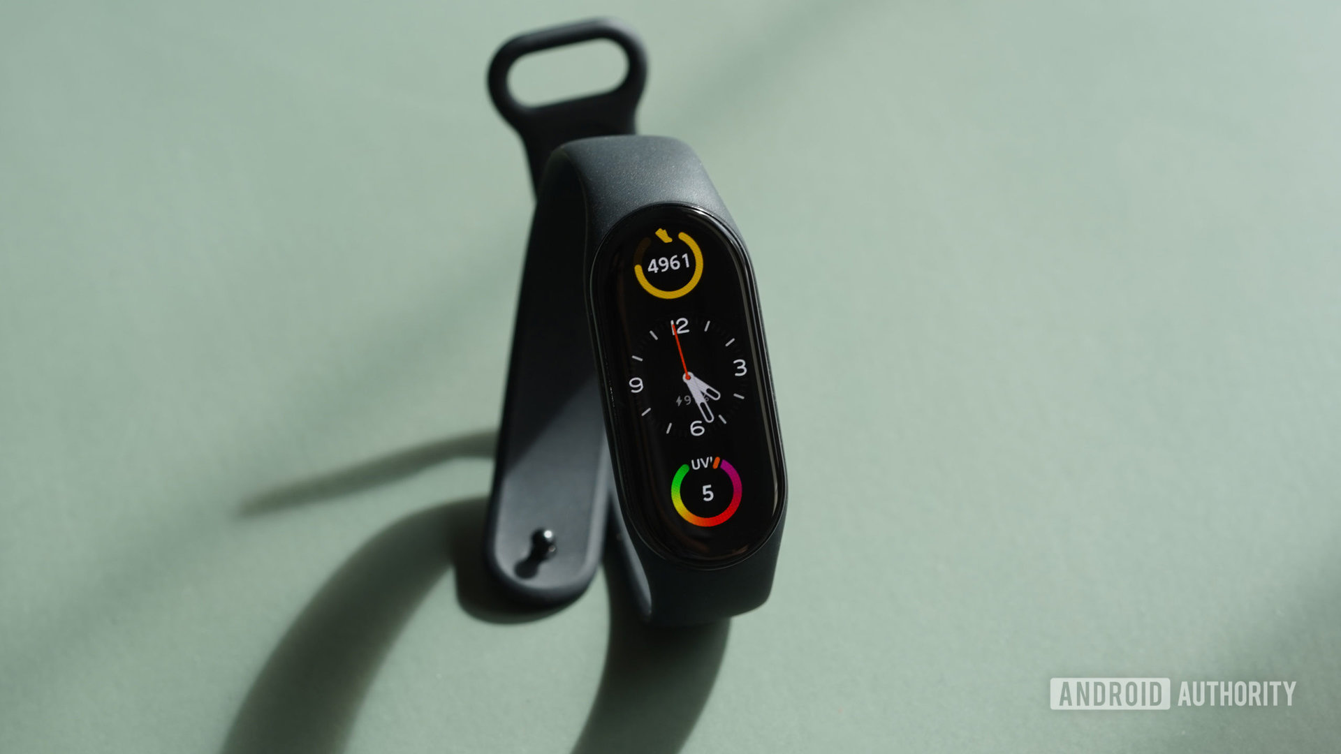 A Xiaomi Mi Band 7 in black rests on a mint yoga mat.