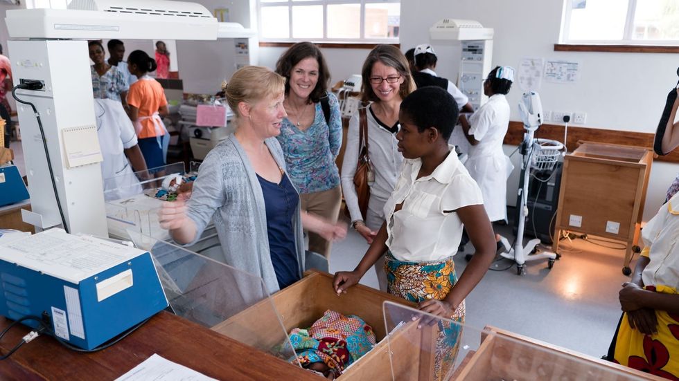 a group of women smiling and talking to each other in a hospital setting