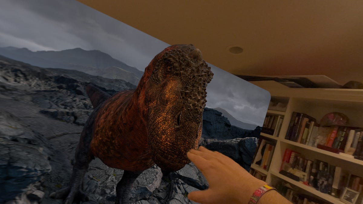 A hand reaching to a virtual dinosaur emerging from a window in an office