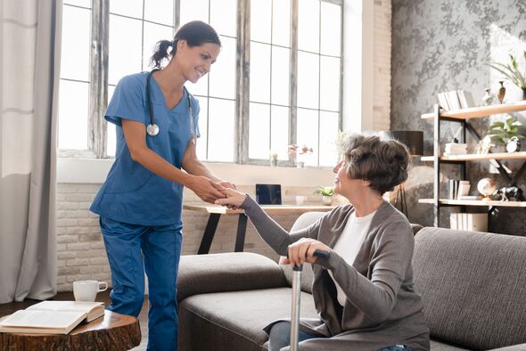 Mature caregiver nurse medical worker helping old elderly senior patient grandmother to stand walk. Geriatrics concept. Disability in motion, immobili