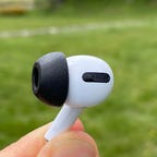 An AirPod Pro earbud with a black Comply foam tip.