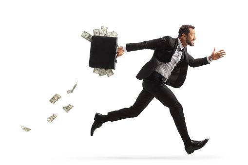 Full length profile shot of a businessman running fast and carrying a briefcase with money