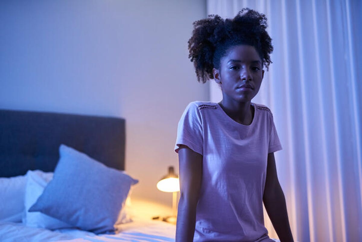 Woman sitting on the edge of her bed because she can't sleep.