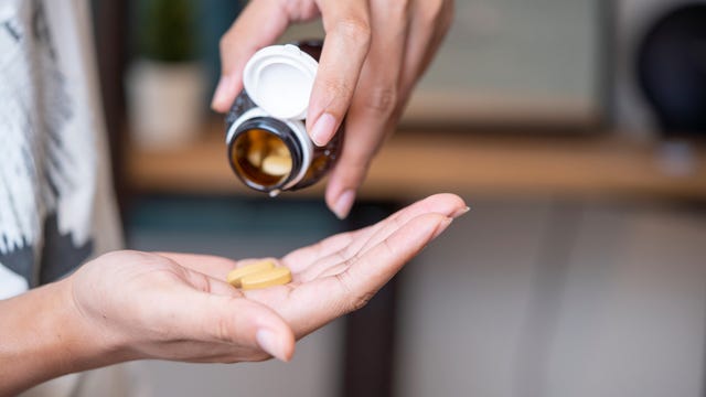 Pouring vitamins on one hand from a bottle