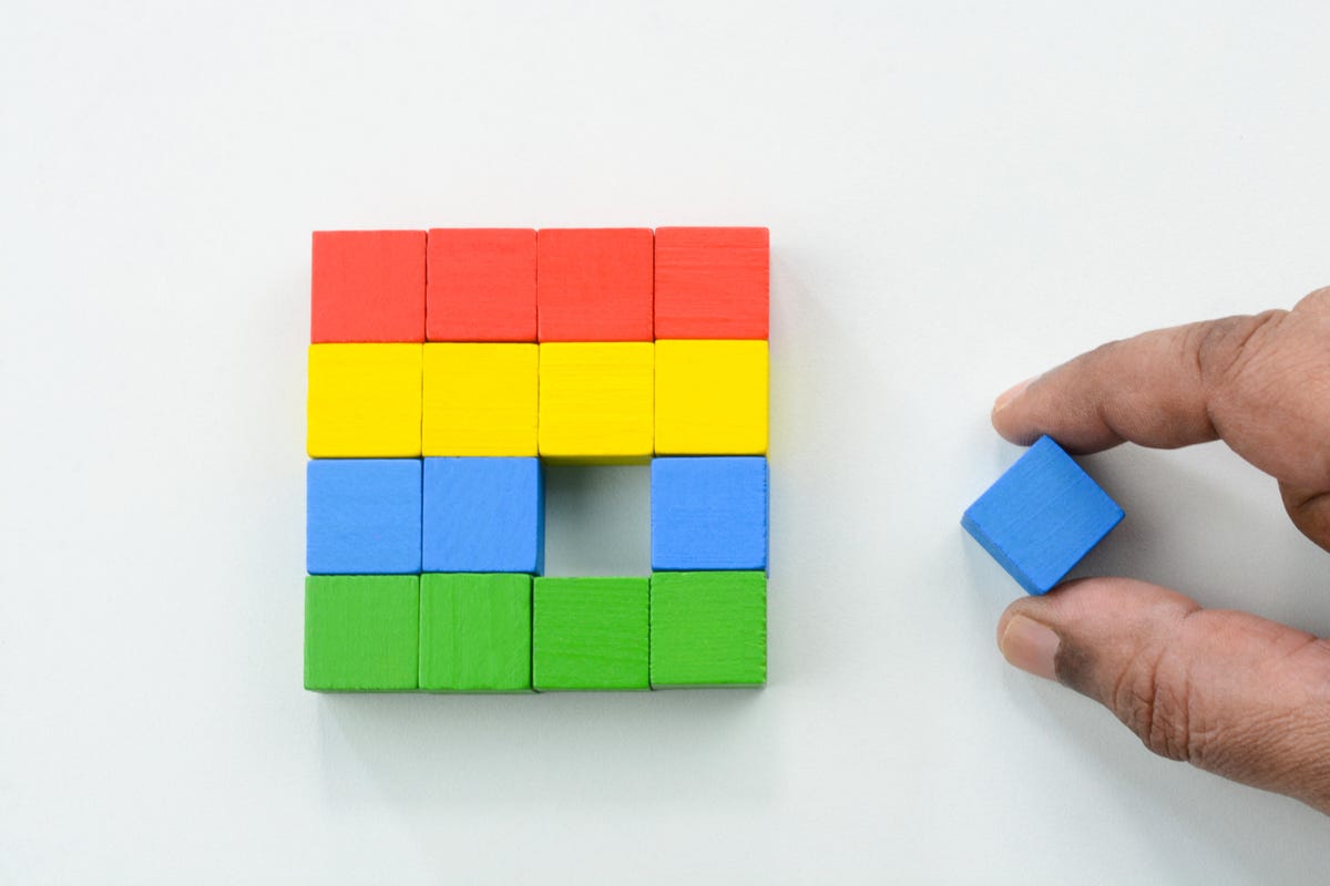 A hand putting the last piece of a rainbow puzzle