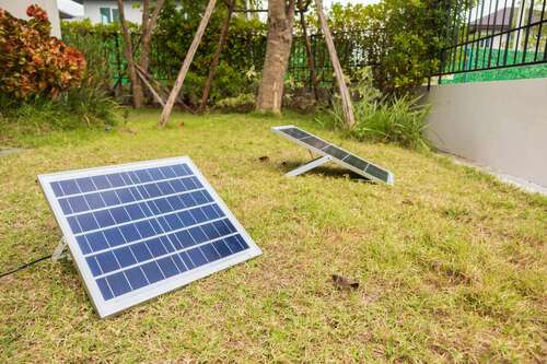 two small solar panels on the ground in a garden.