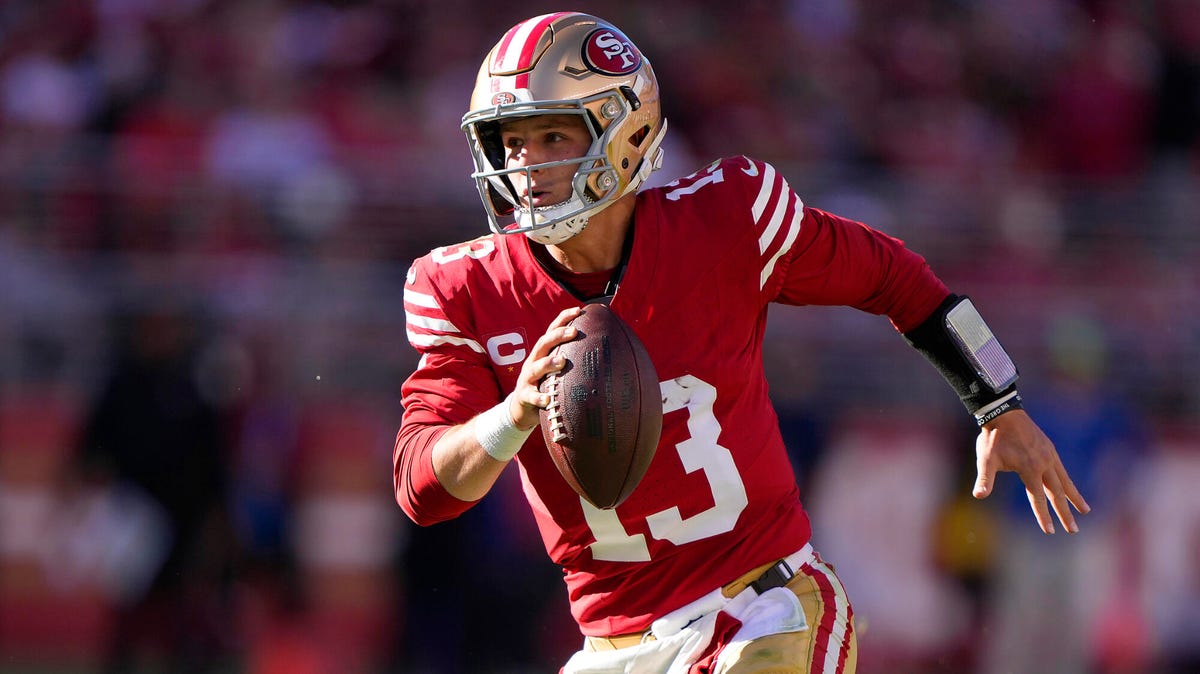 Brock Purdy of the San Francisco 49ers running with the ball gripped in his right hand.