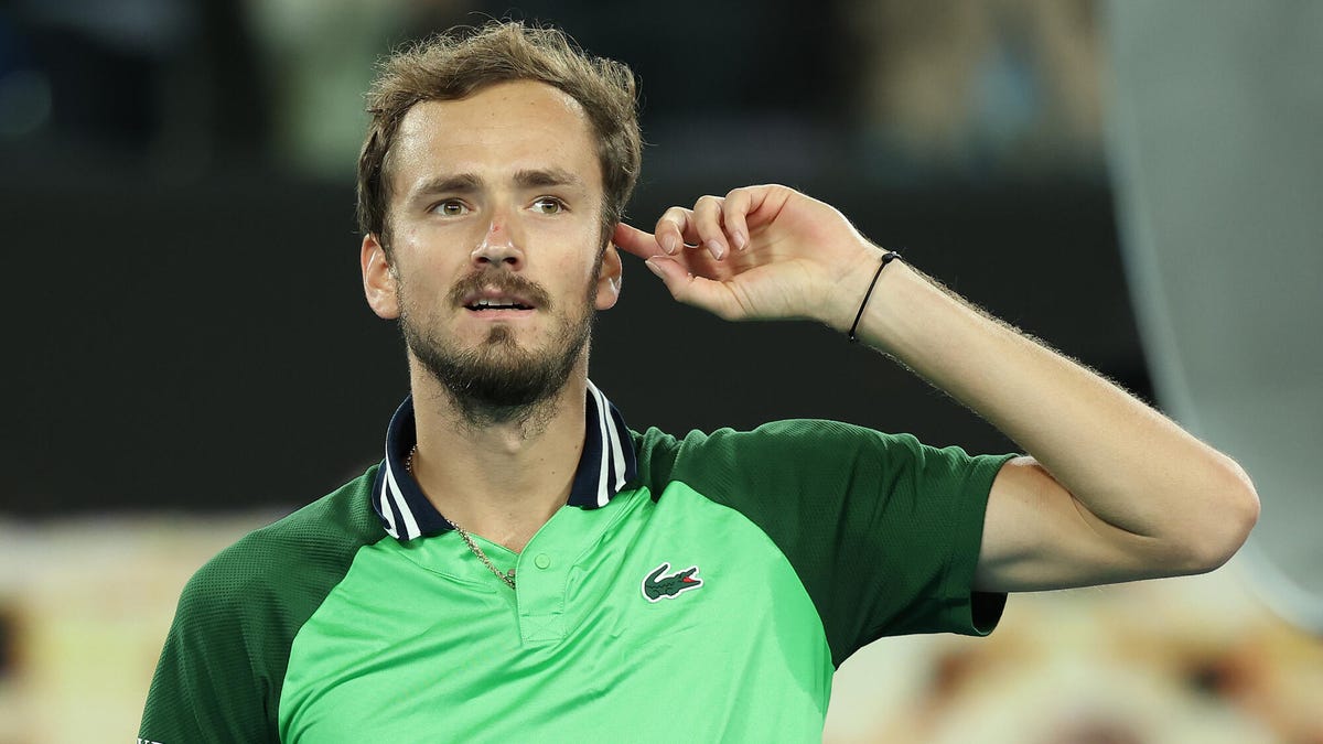 Tennis player Daniil Medvedev living his left hand to his ear.