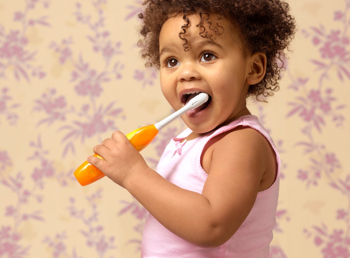 Portrait of a child brushing her teeth with an electric toothbrush