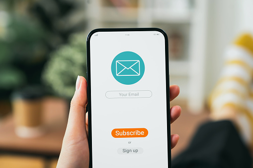 Hand holding smartphone and shows a digital screen of subscribe email notifications or sign up.