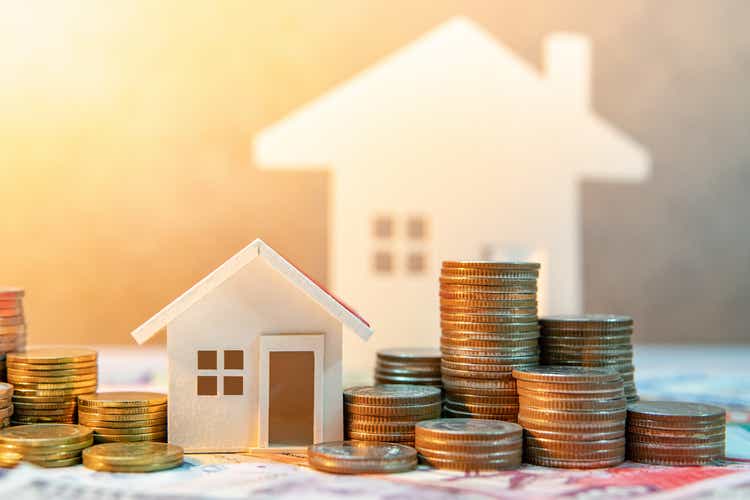 Real estate or property investment. Home mortgage loan rate. Saving money for retirement concept. Coin stack on international banknotes with house model on table. Business growth background