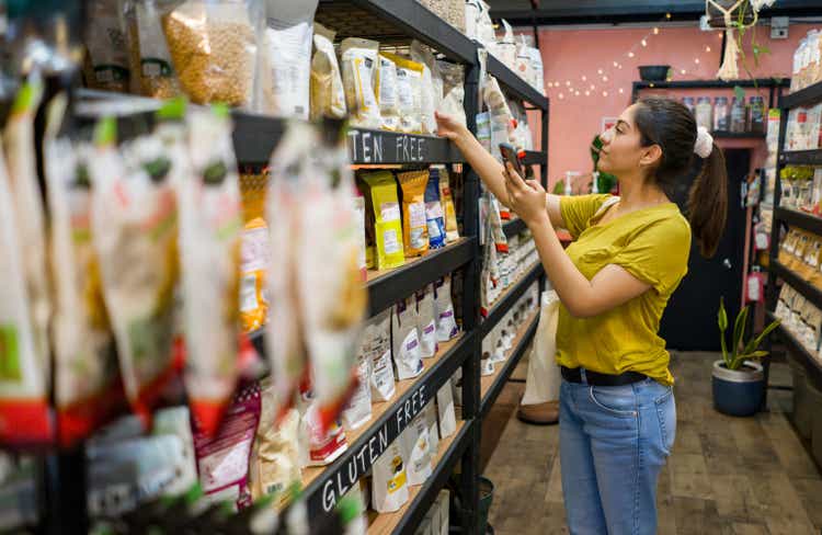 Woman shopping at a food market and scanning products with her cell phone