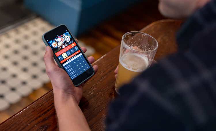 Man gambling online while drinking beer at the pub