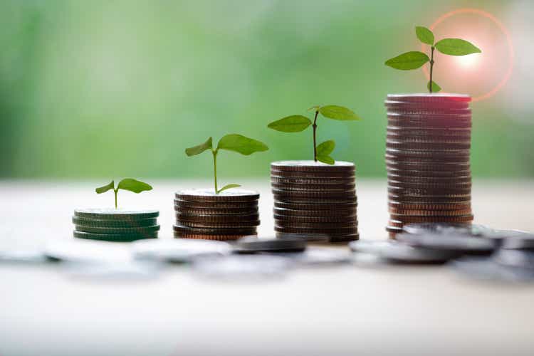 Save money for prepare in the future. Tree growing on coin of stacking coins with green bokeh background.