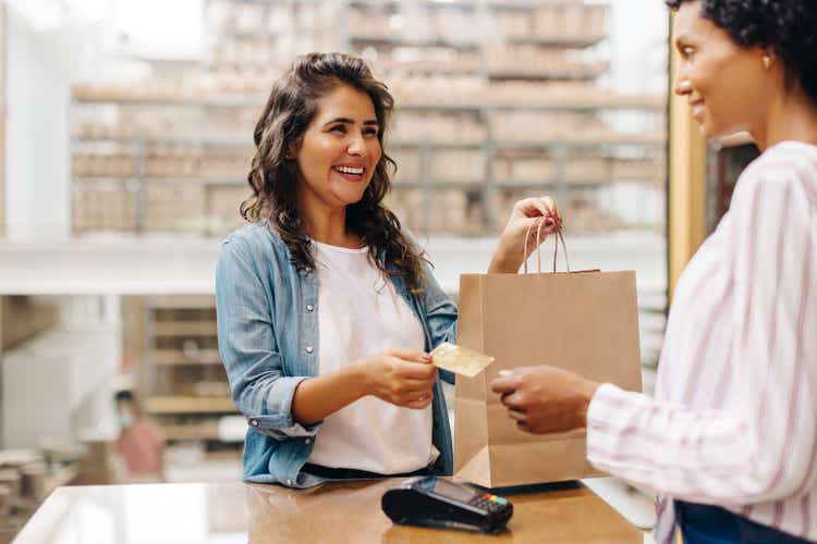 Happy female customer paying with a credit card in a ceramic store