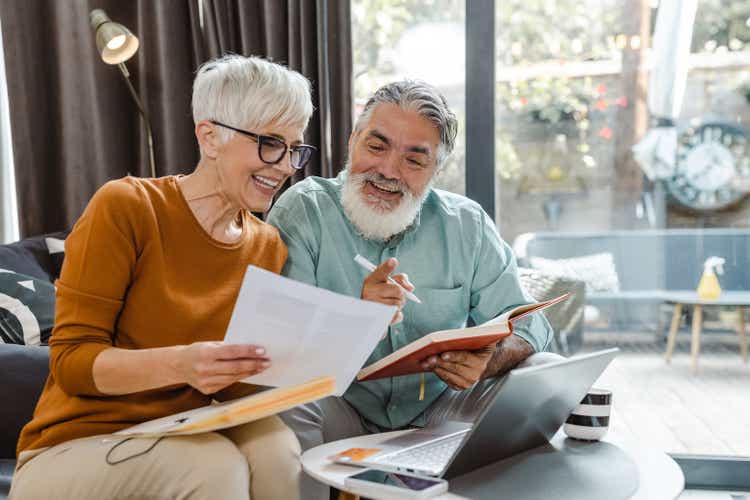 Senior couple discussing home finances and using laptop