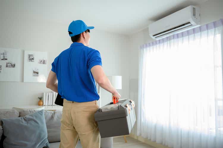 An Asian young Technician service man wearing blue uniform checking , cleaning air conditioner in home