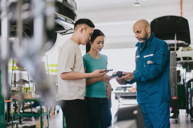 Young Adult Asian couple making payment for their car servicing