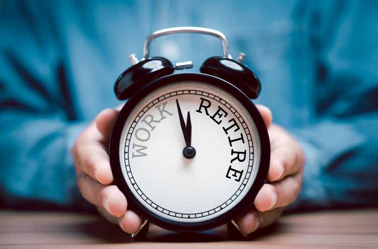 Businessman holding black alarm clock with clockwise countdown from work to retirement.