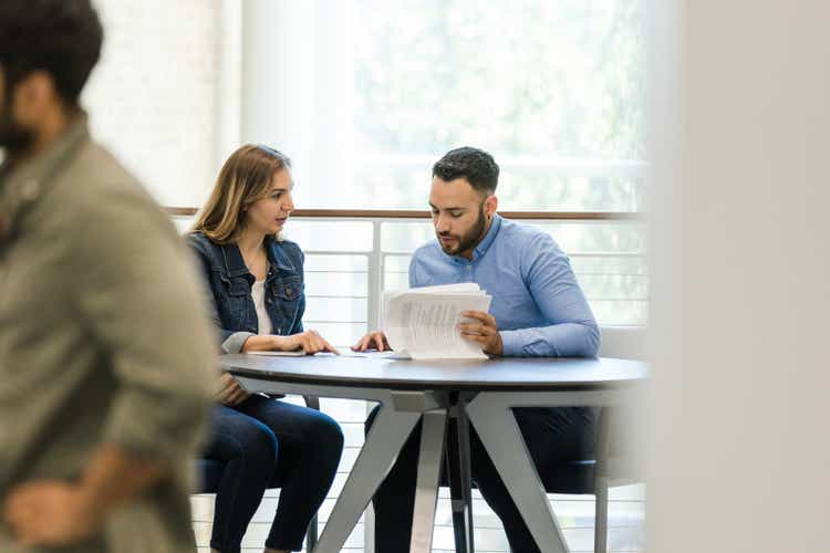 Mid adult woman and young adult man discuss work reports