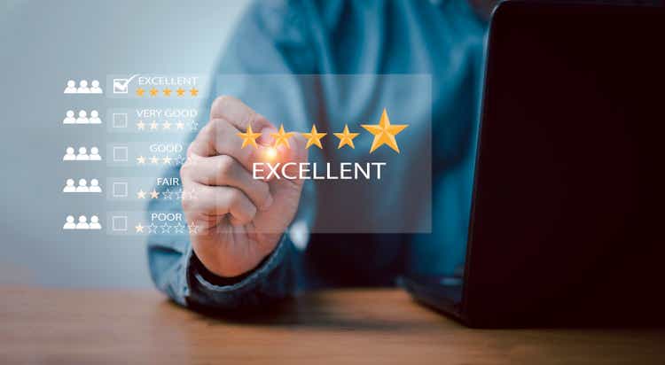 Businessman using laptop computer to give golden five stars for client the best satisfaction evaluation survey after use product and service concept.