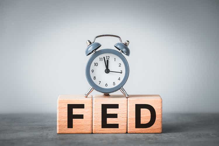 The abbreviation FED on wooden blocks and an alarm clock showing the time at five to twelve, Federal Reserve System United States Of America, FED Decision Announcement