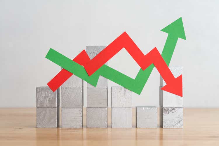 Wood bar chart and arrow red green graph chart volatility moving up and down on wooden table background.