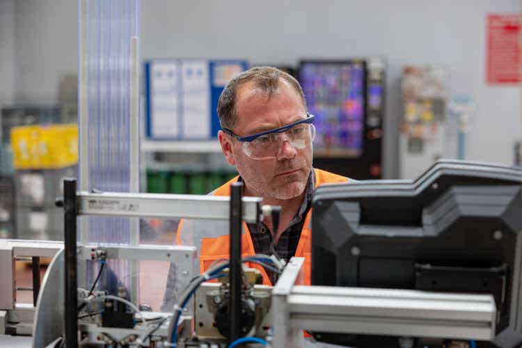 Male industrial worker working with manufacturing equipment in a factory