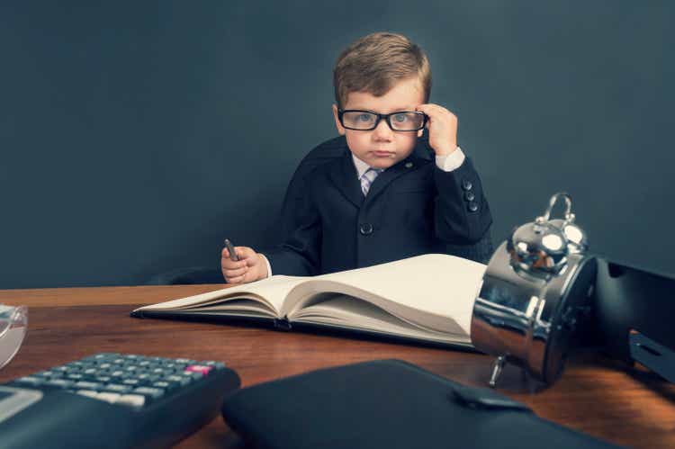 Young boy dressed in suit working at desk.