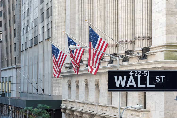 Wall street sign in New York City with New York Stock Exchange background.